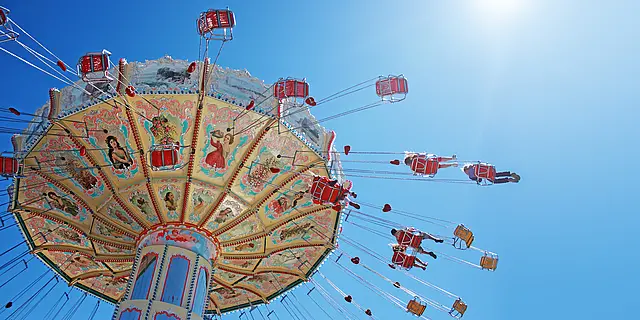Ein Volksfest-Karussell dreht sich unter strahlend blauem Himmel.